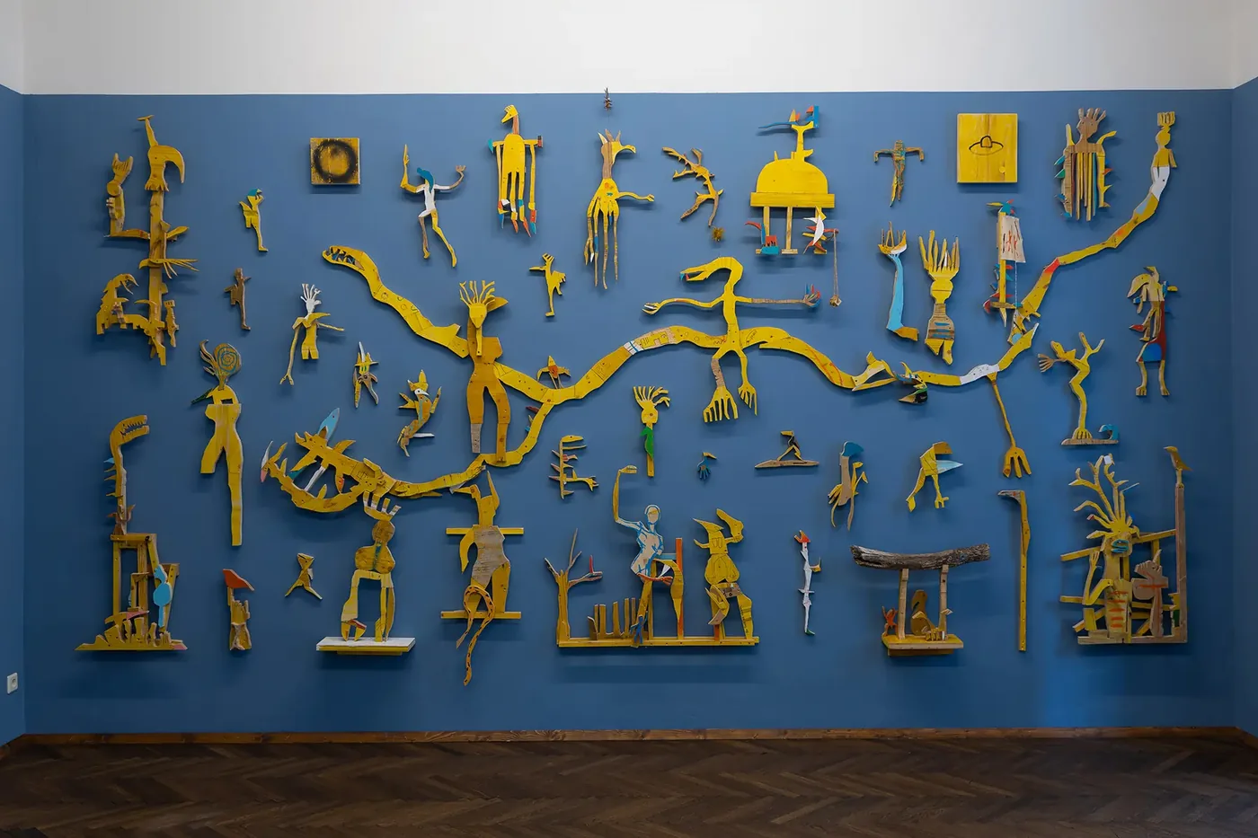 Full wall view of the yellow wood cutout figure installation by Ernst Koslitsch, Beings & Creatures, rotor, Graz