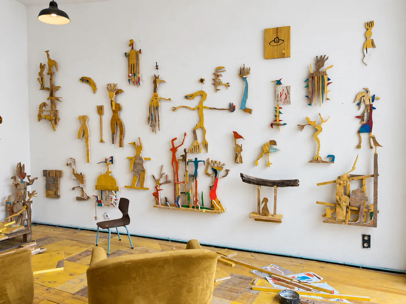 Studio wall covered with yellow wood cutout creature figures in progress, work for Beings & Creatures, rotor, Graz, Ernst Koslitsch