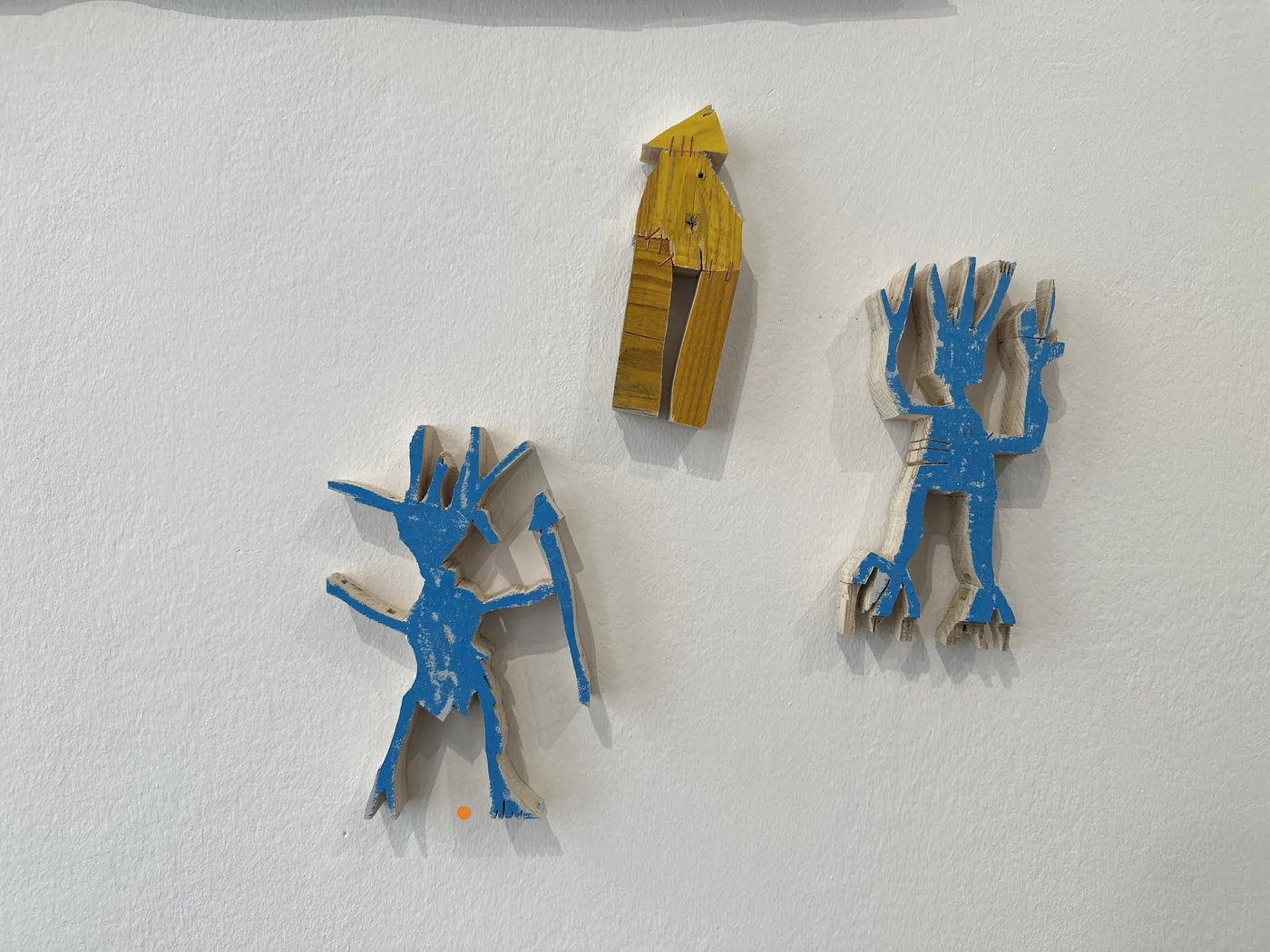 Three small painted wood wall figures, one yellow and two blue, Ernst Koslitsch, Cosmic Trigger – Respawn, Bildraum 07