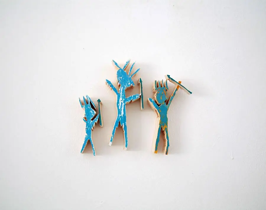 Three small blue painted wood figures on wall