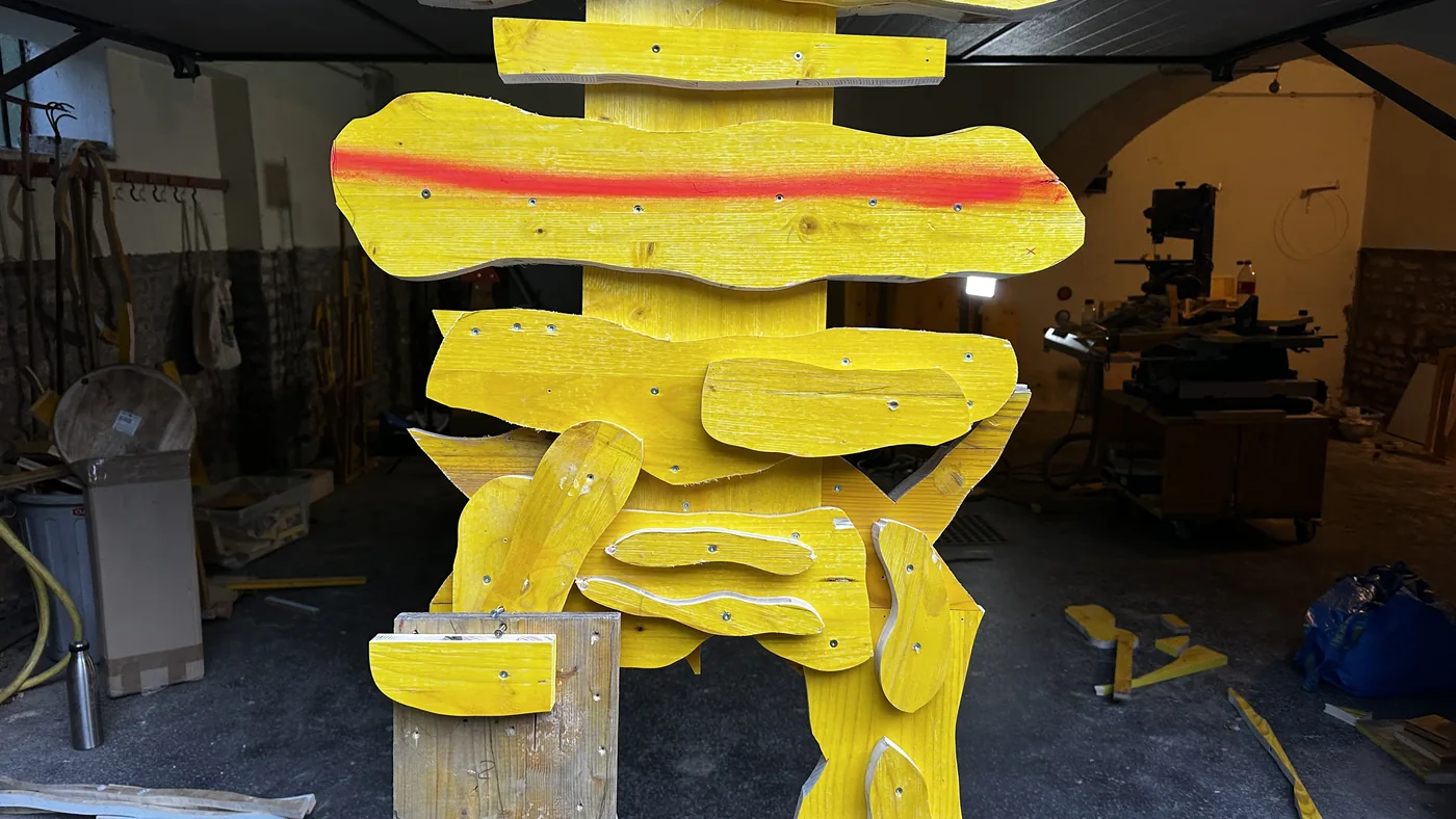 Close-up of a wooden Echo Keeper sculpture during fabrication, with red paint markings, in the workshop