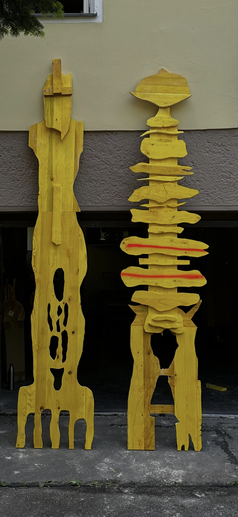 Echo Keepers 1 + 2, two wooden sculptures by Ernst Koslitsch, standing side by side in evening light before installation