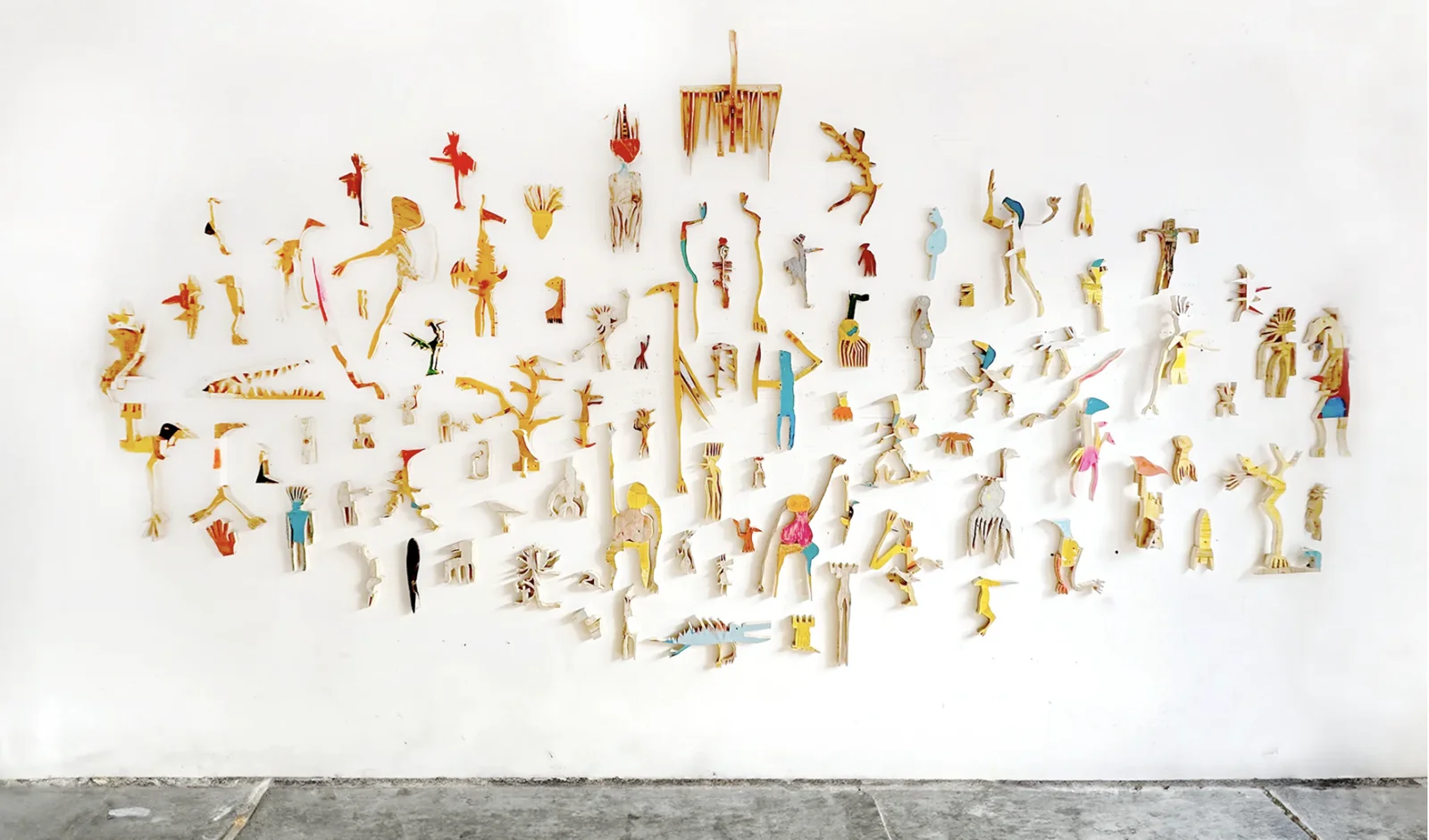 Wide wall installation of small painted wood cutout figures by Ernst Koslitsch, EX-SITU, Nationalmuseum Sarajevo