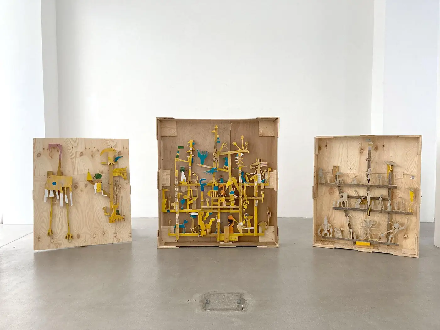 Three yellow wood sculptures on crate backs, Spark Art Fair booth