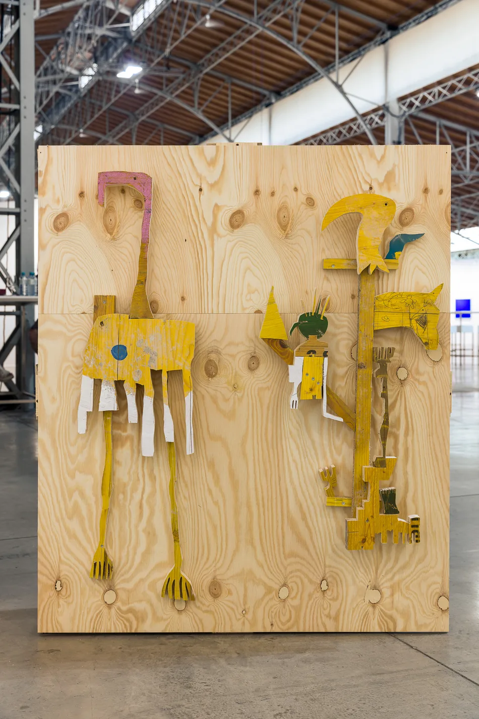 Two yellow wood wall sculptures mounted on a raw plywood panel, Spark Art Fair booth, Ernst Koslitsch