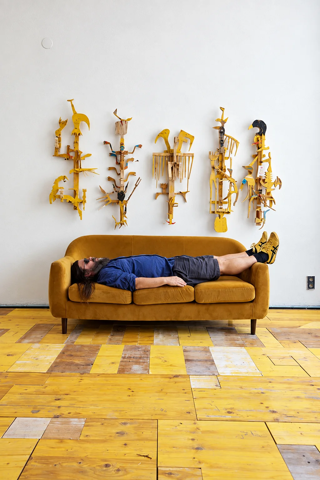 Ernst Koslitsch in his studio, below a row of yellow wall sculptures