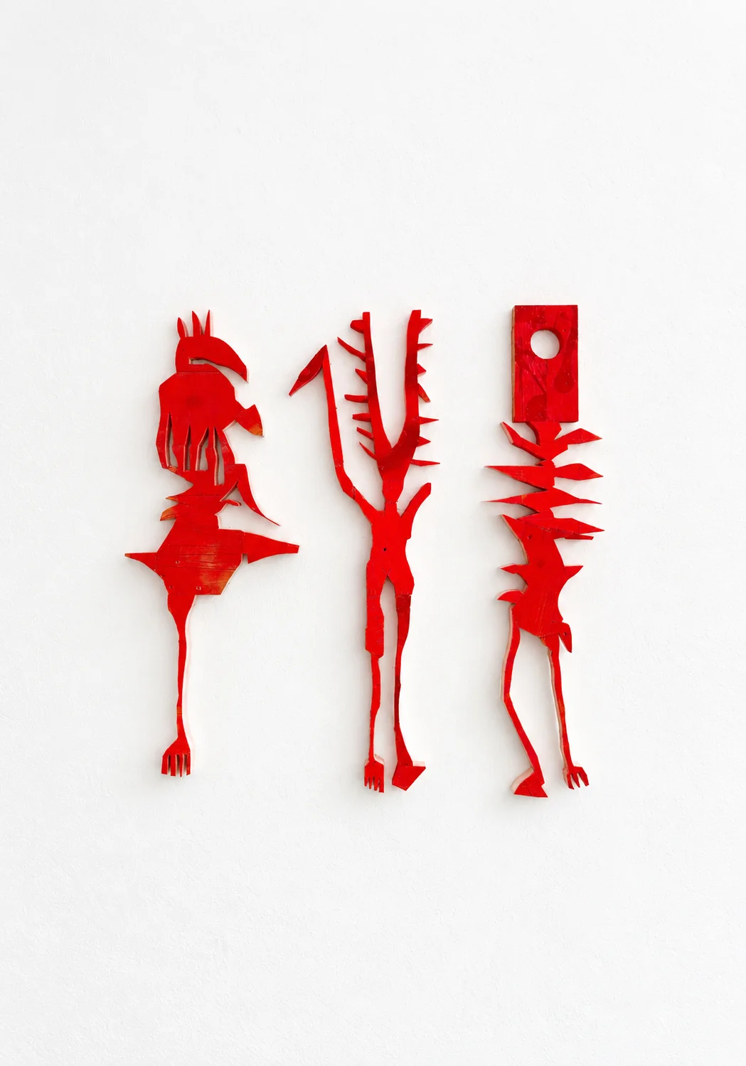 Three red wood cutout figures, studio view, Ernst Koslitsch