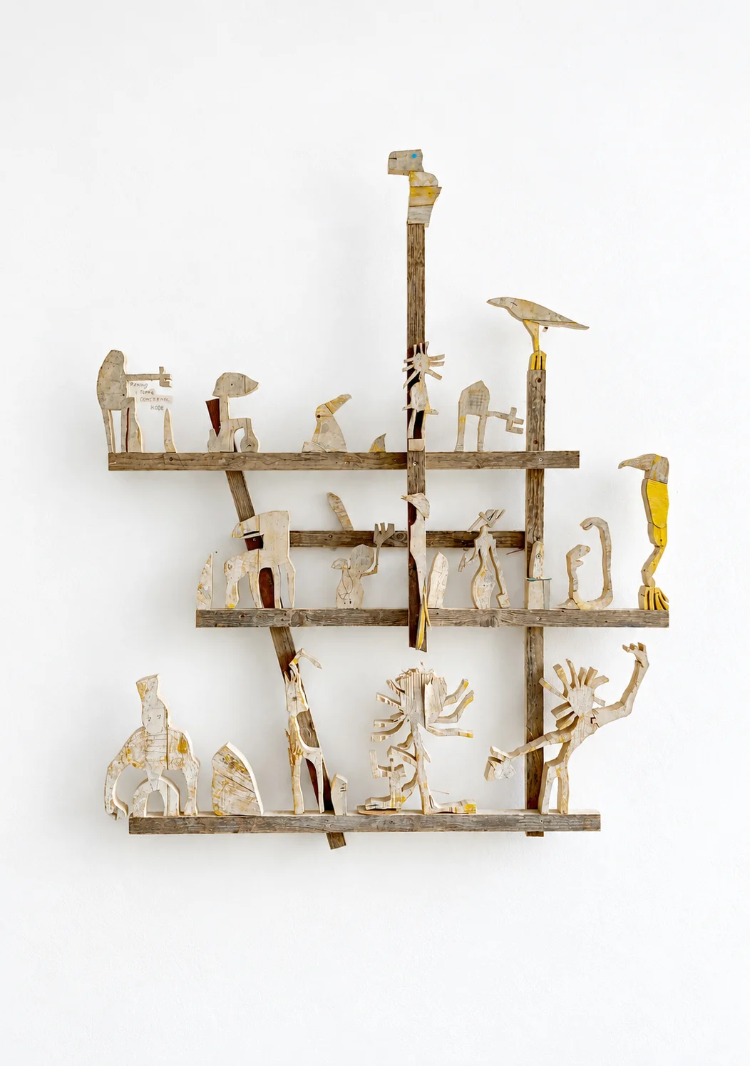 Weathered wood figures arranged on horizontal shelves, studio view, Ernst Koslitsch